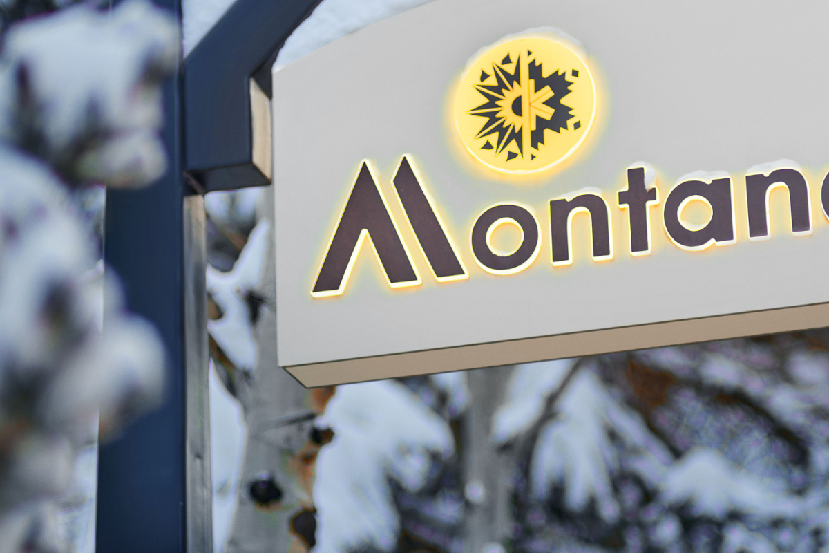 A sign with the word "Montaneros" and a sun or snowflake symbol is shown, partially obscured by snowy trees in the background.